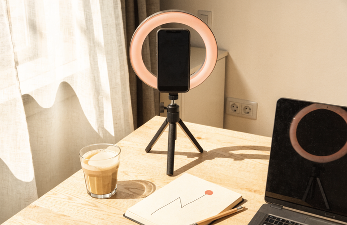 Content creation desk with a phone on a ring light, coffee and a growth-line notebook, by Clayit. in the UAE